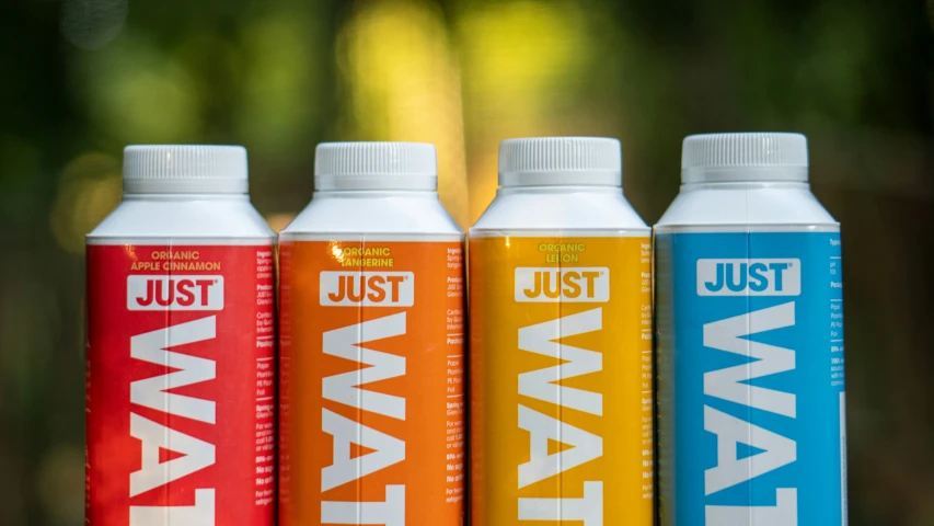 three drinks, one orange, one red, all sitting in front of a camera