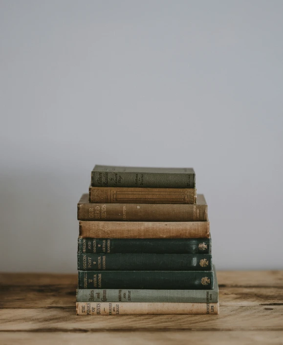 a stack of books are on top of a wooden table