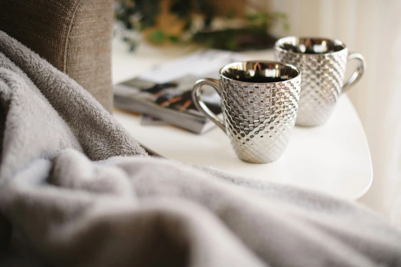 two cups sitting on top of a table next to a curtain