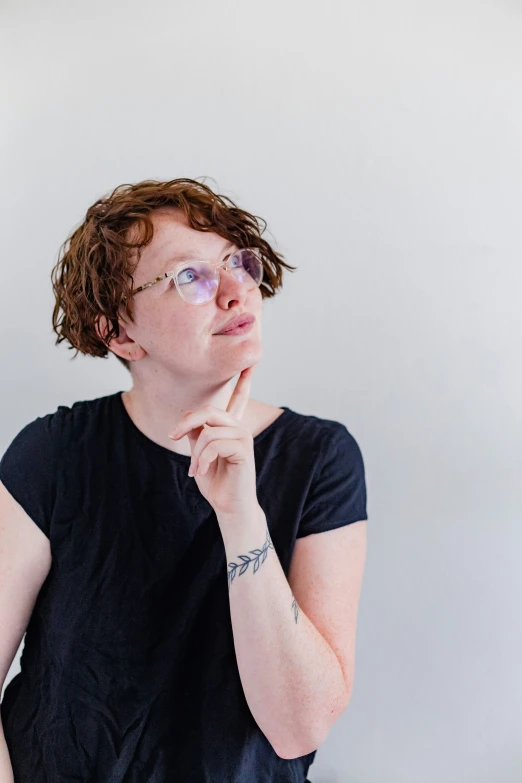 a woman wearing glasses holding her chin up to her chest