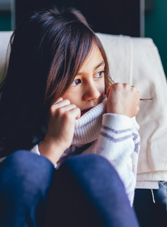 the girl is sitting on the couch with her hand on her face