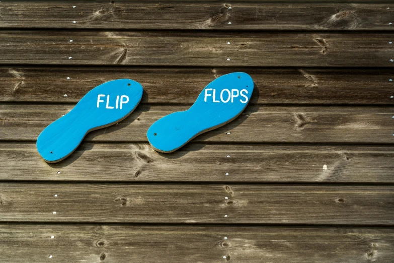 two flip flops are painted on top of a wooden plank