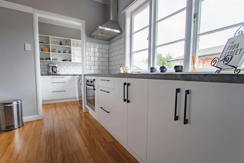 a kitchen with a large window and hardwood floors