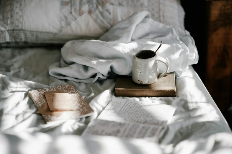 a book, cup and bookmark are placed on a bed