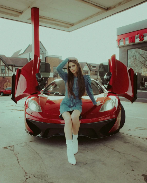 girl sitting on the hood of a red car