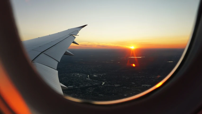 a plane window over the sun sets