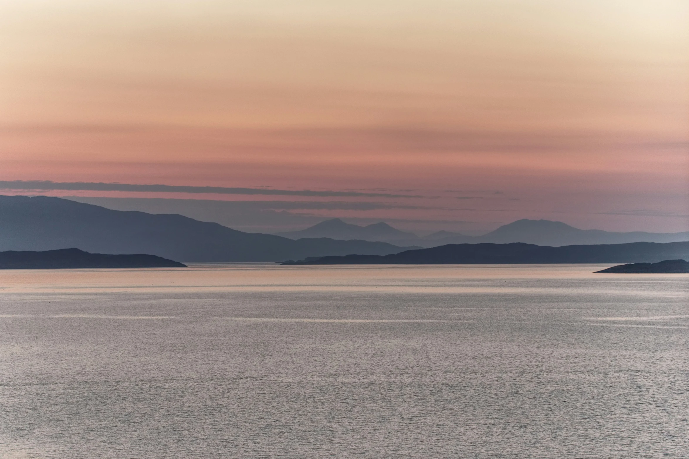 the mountains of the water are behind a boat