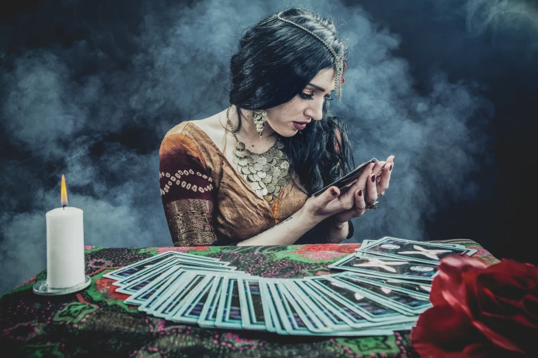 woman with veil and veillet holding a smart phone, next to playing cards on table