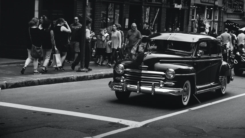 a vintage truck driving down a busy street near people