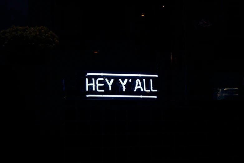 the neon sign says hey y'all outside