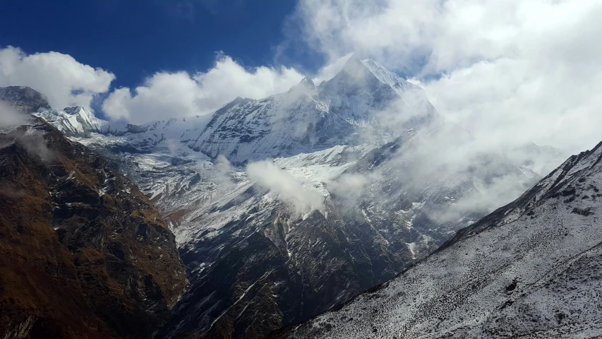 clouds are hovering over snow - covered mountains in the eastern desert