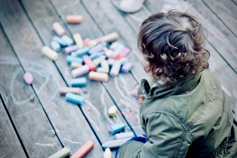 a little girl sitting in front of a number of chalk crayons