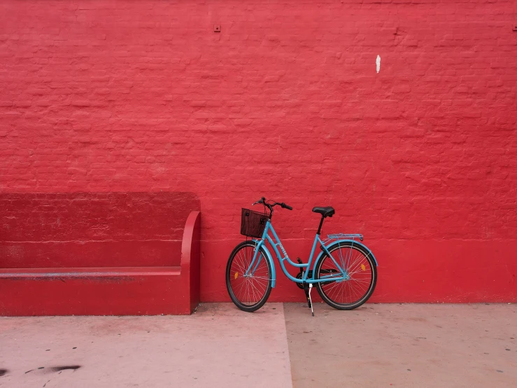 a blue bicycle is leaning against a red wall