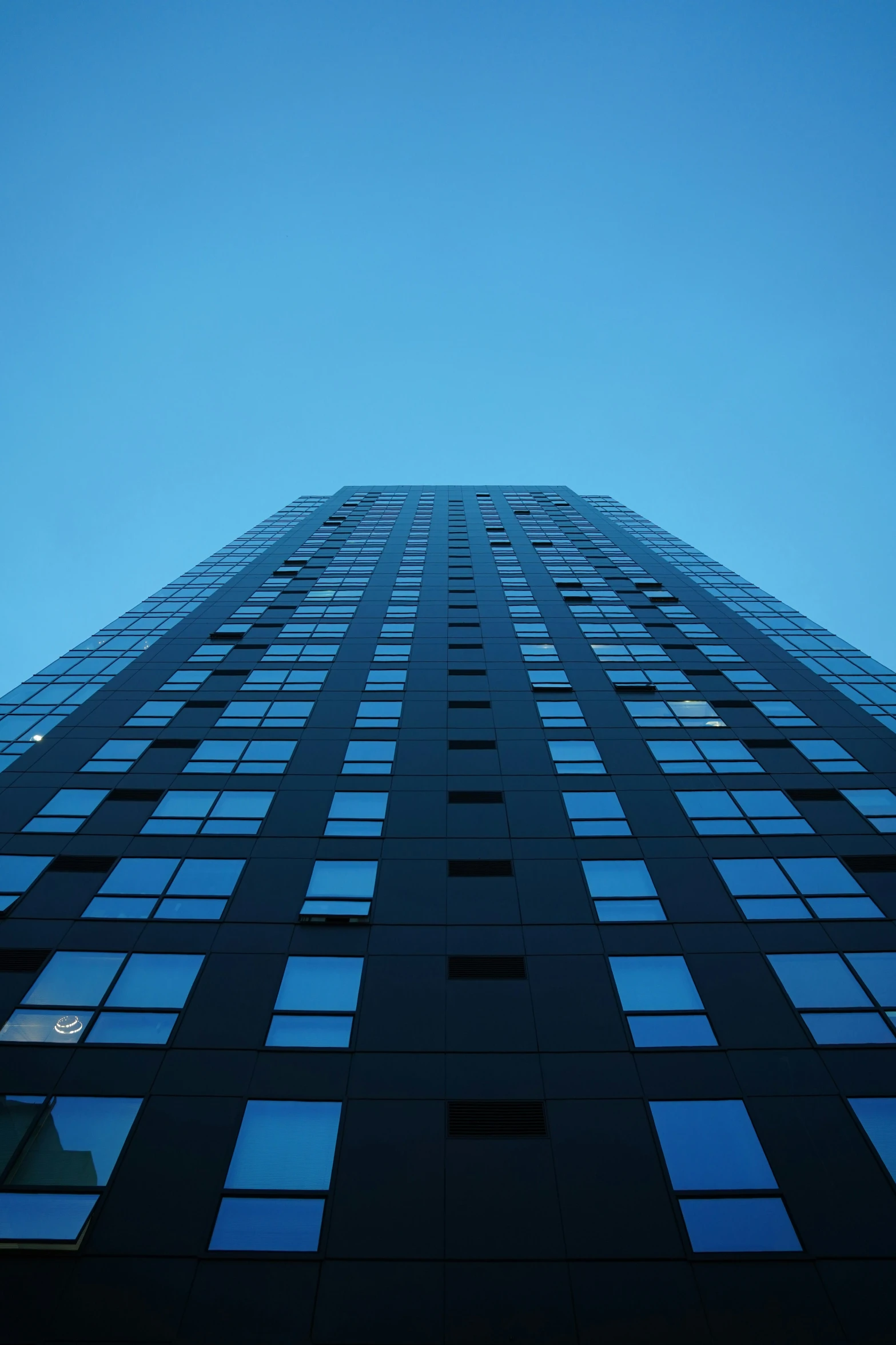 high rise office building silhouetted against a blue sky