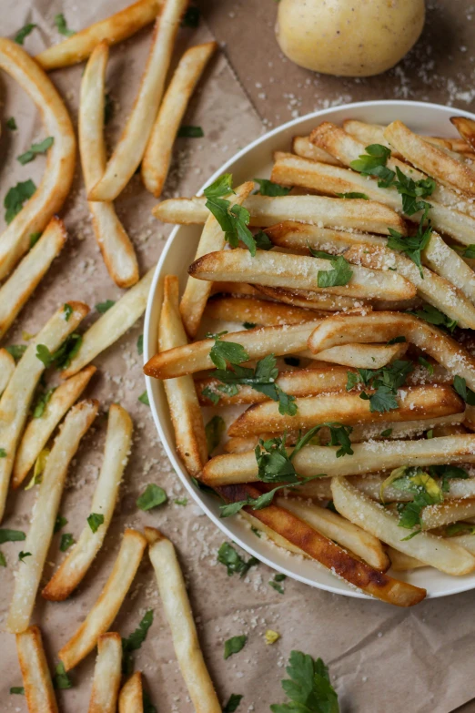 fries with cilantro and parsley are in a bowl next to an egg