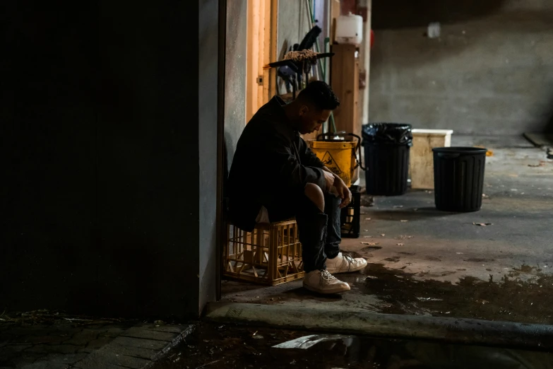 a person sitting on a chair with his legs crossed and legs crossed, next to a cage filled with birds