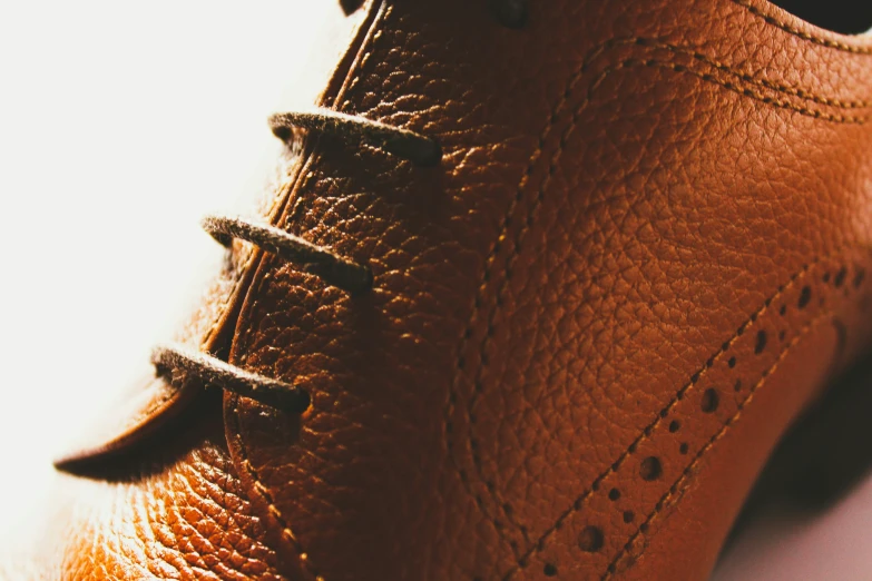 an orange shoe with brown stitchs on the toe