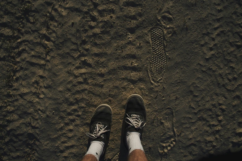 a man standing in the dirt looking down at his shoes