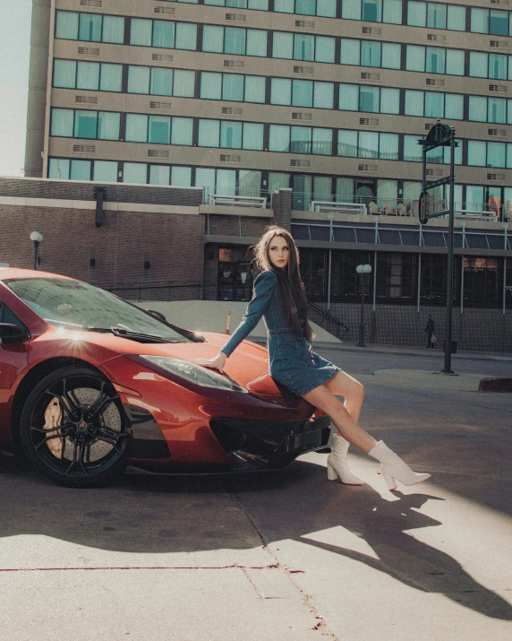 girl sitting on top of a red car with very high heels