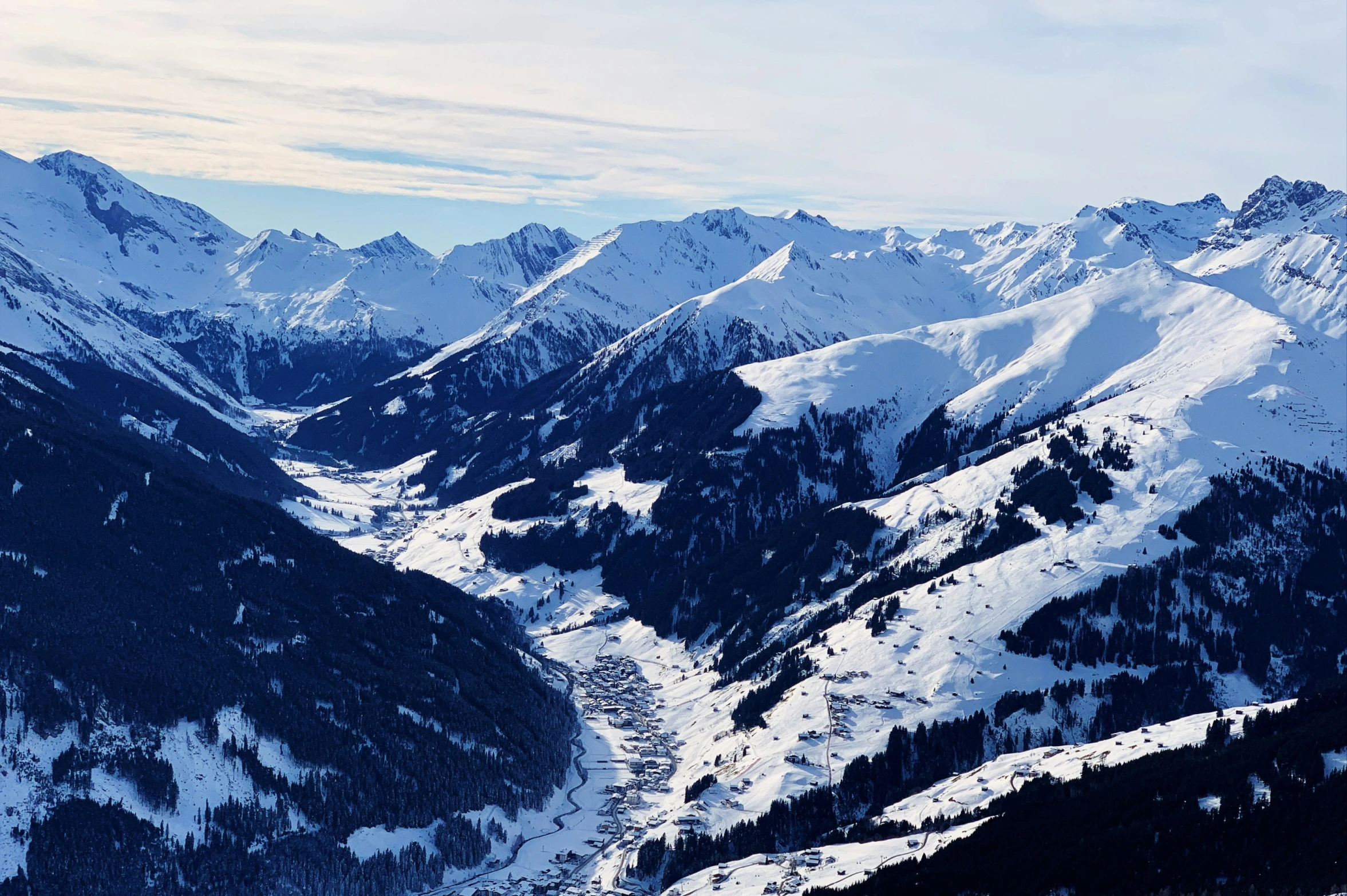 snow capped mountains are covered in green grass