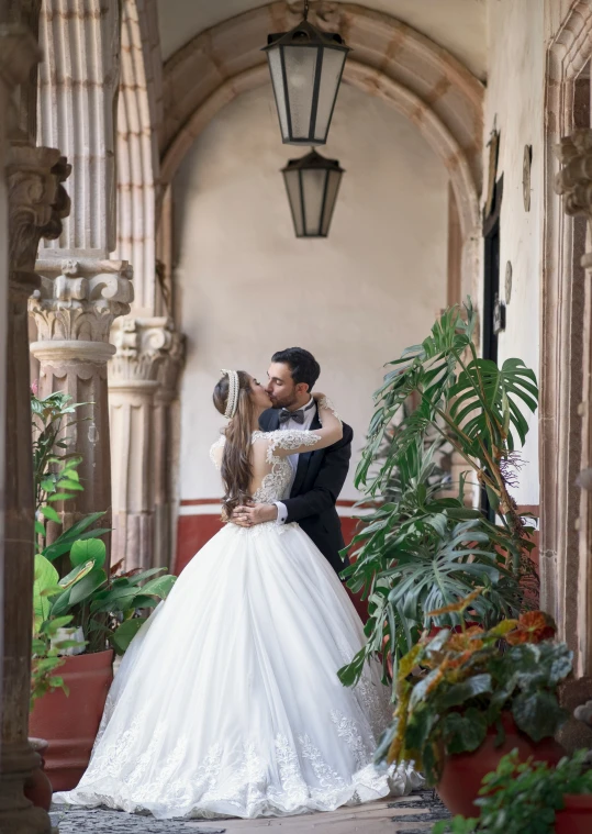 a bride and groom standing in an old - fashioned setting by a beautiful plant