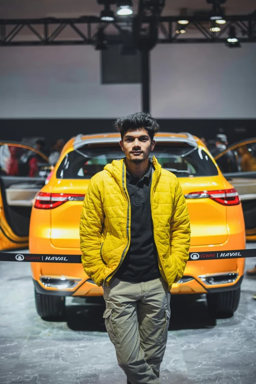 a man standing in front of an orange car