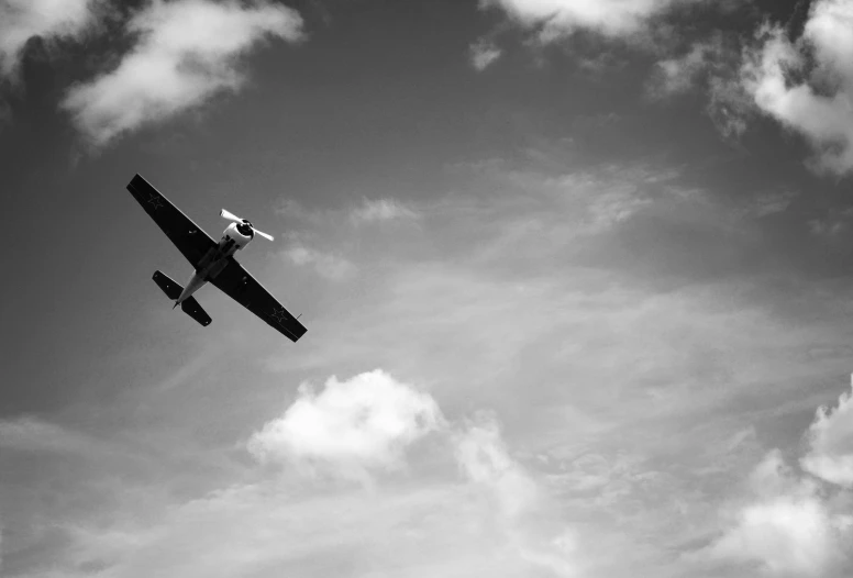 an air plane is flying against the cloudy sky