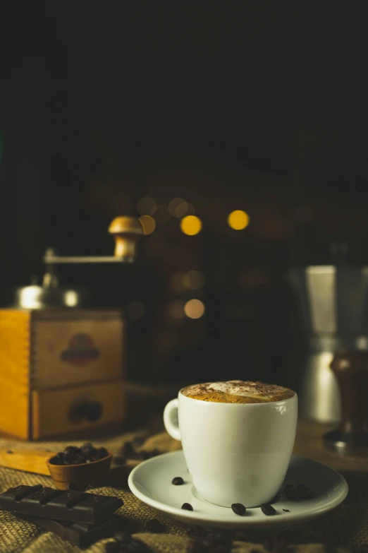 an espresso is on a saucer near some coffee grinders