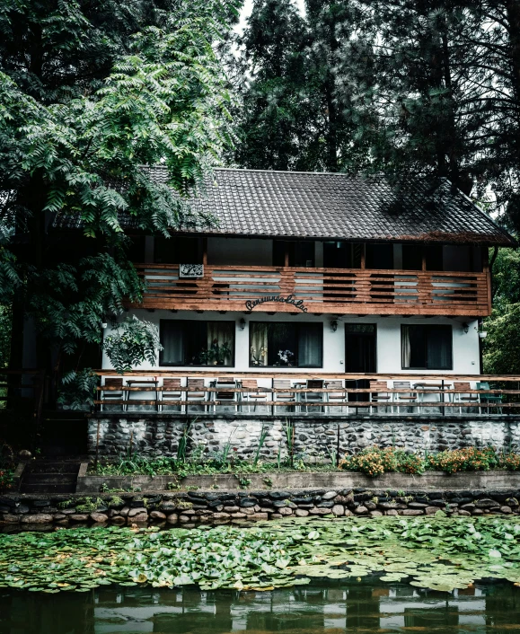 a large wooden building next to a lake with water lily