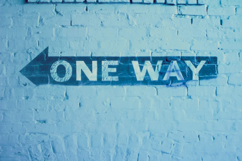 a one way street sign on a stone wall