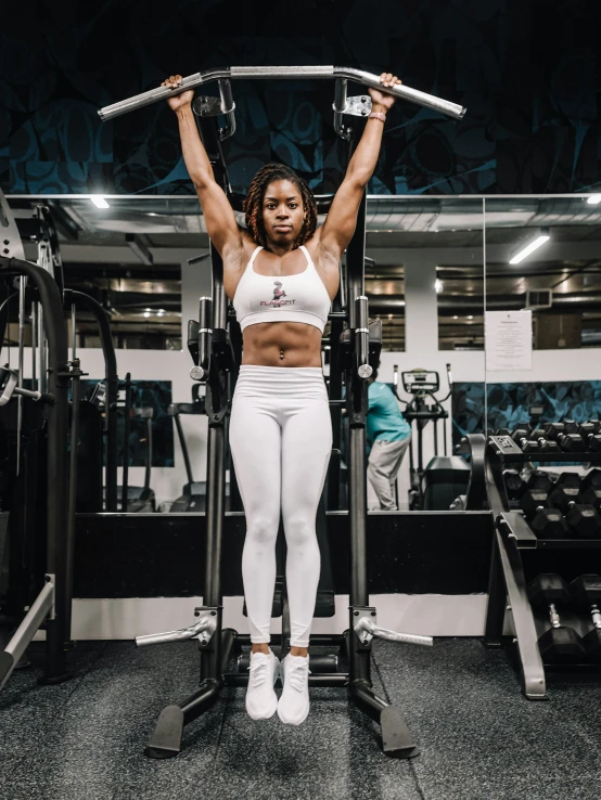a woman standing in a gym holding some barbells