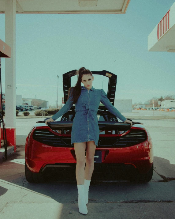 the woman is posing next to a red sports car