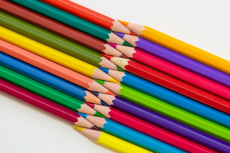 a stack of colored pencils sits with one single colored pencil next to it