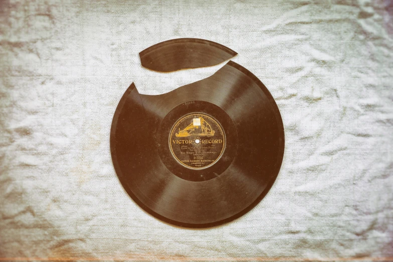 a black record with gold writing is sitting on a white sheet