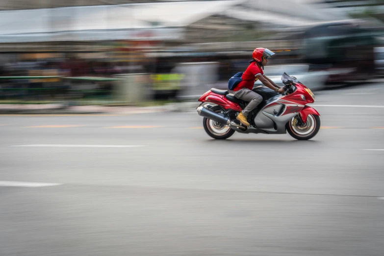 person on red motorbike rounding a corner while blurry in background