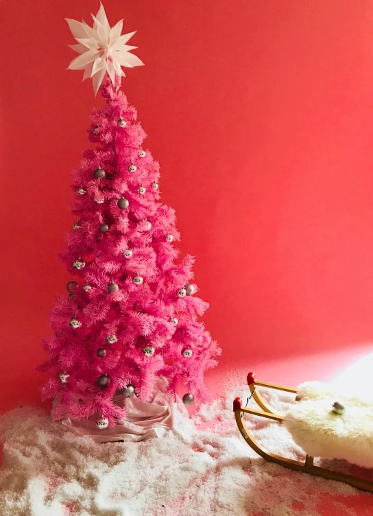 a bright pink christmas tree against a pink wall