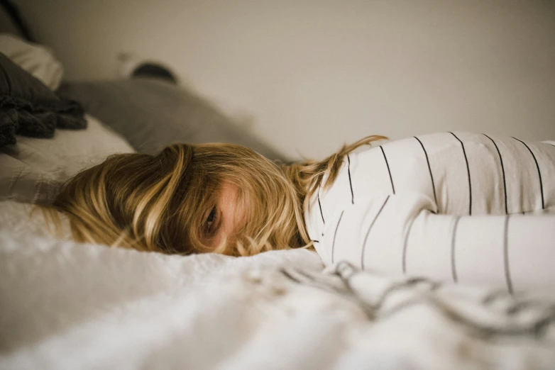 woman hiding behind white sheets on bed