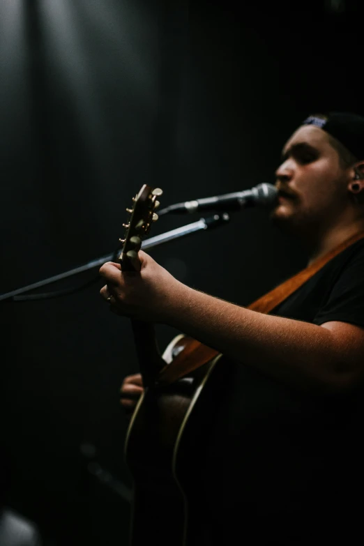 man playing guitar while singing into microphone