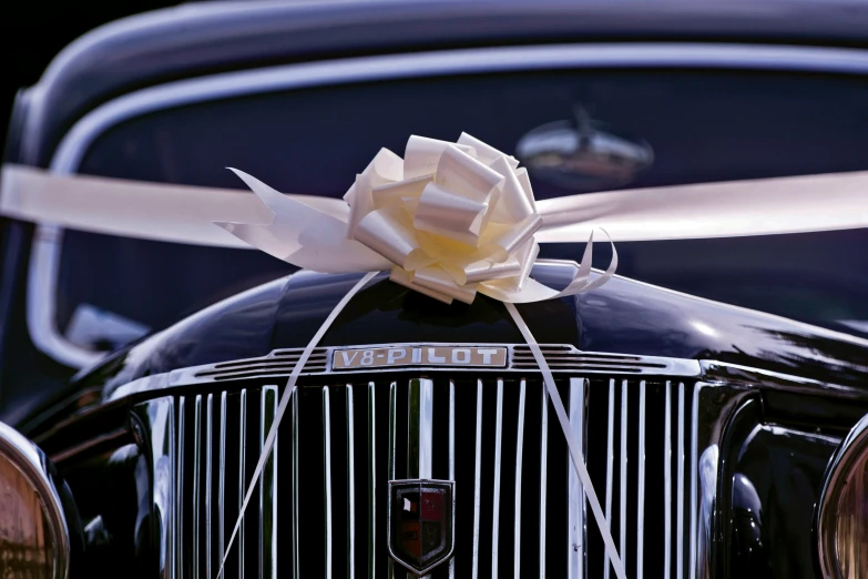 an old style car with a white rose on top