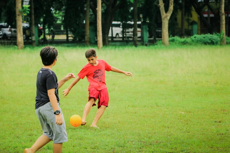 two s kicking around a yellow ball on the field