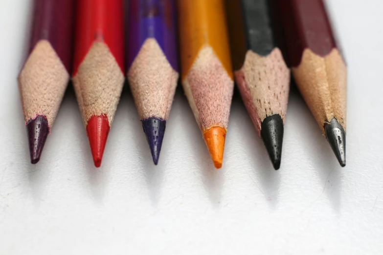 a row of different colored pencils with erases