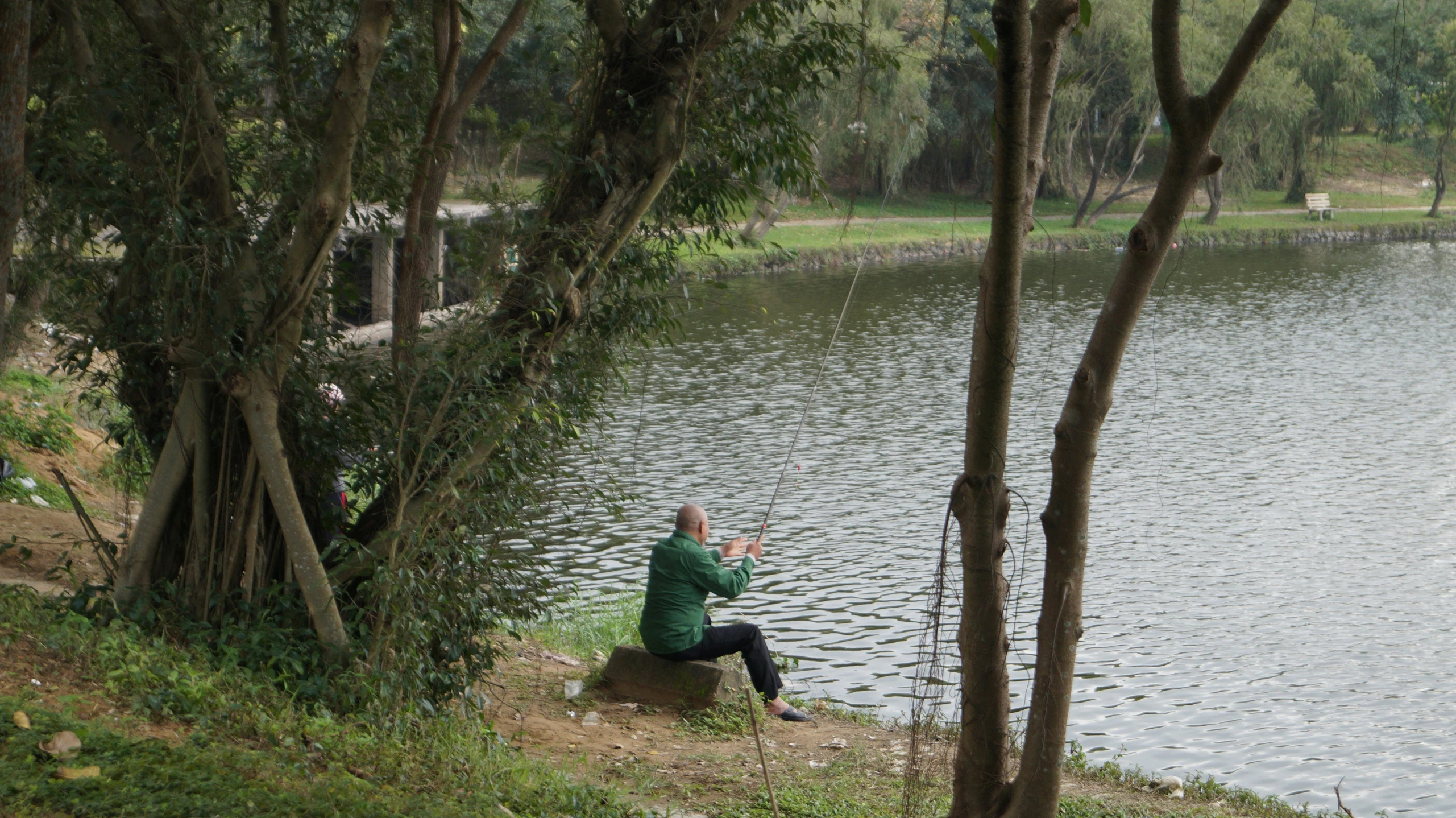 a person sitting on a rock near a lake