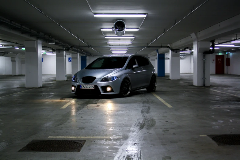 a silver car parked in a parking lot with lights on