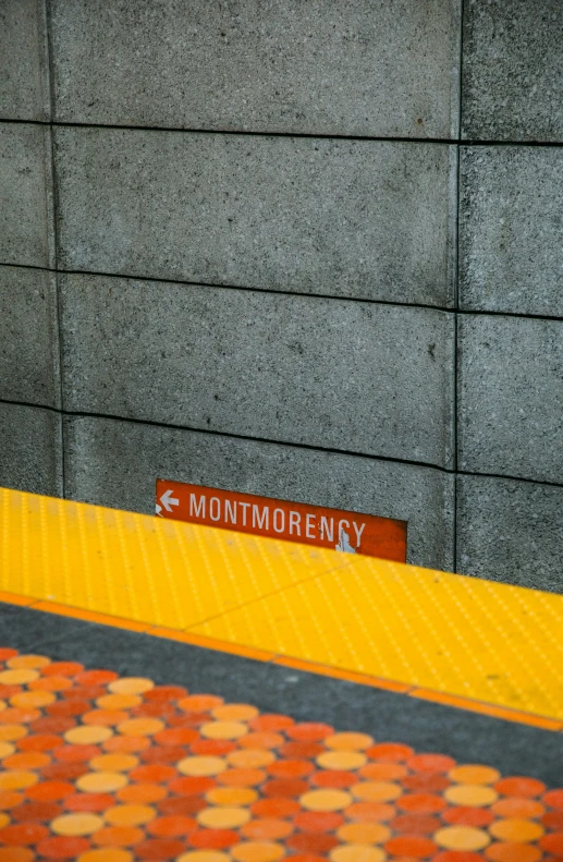 a street sign is on the corner in front of a wall