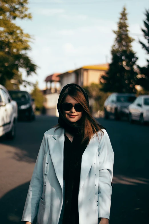 woman wearing a blue jacket and black dress standing on a street