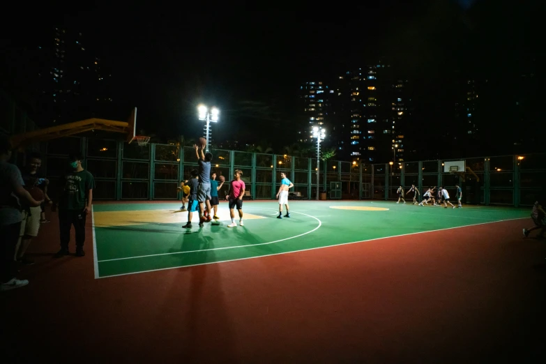 people walking around on the basketball court at night