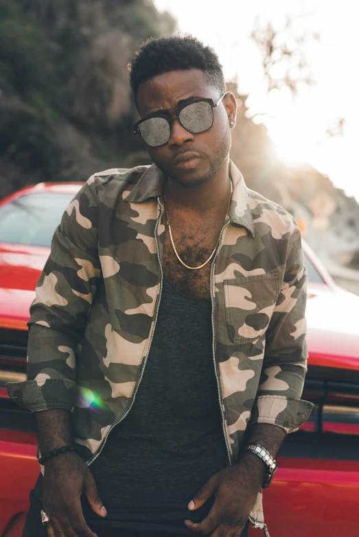 a man wearing sunglasses standing next to a red car