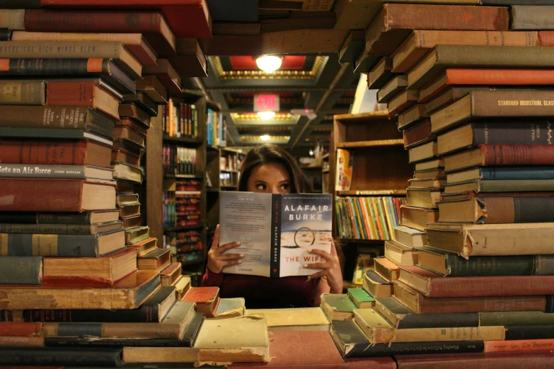 a woman sitting at a liry reading and smiling