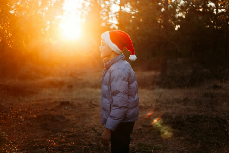 a man wearing a santa hat with the sun behind him