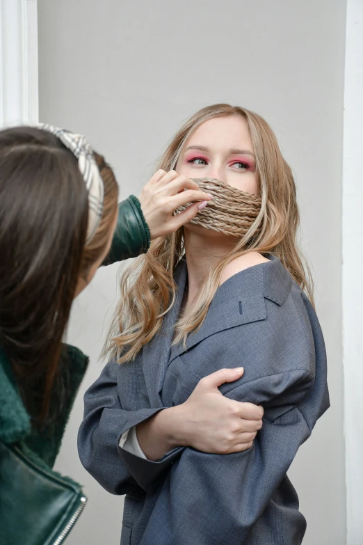 woman brushes her face next to another woman